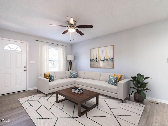 living room featuring a textured ceiling, light hardwood / wood-style floors, and ceiling fan