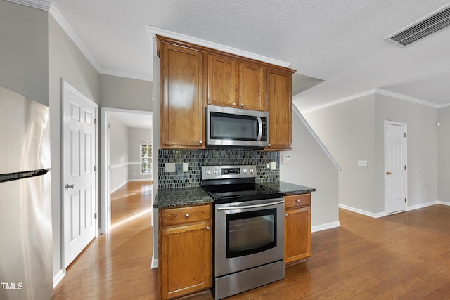 kitchen featuring appliances with stainless steel finishes, light wood-type flooring, and dark stone countertops