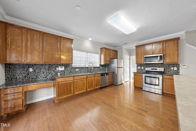 kitchen with stainless steel appliances, light hardwood / wood-style flooring, crown molding, and sink