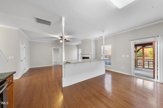 kitchen with a textured ceiling, ceiling fan, dark hardwood / wood-style flooring, and a breakfast bar area