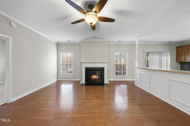 unfurnished living room with a wealth of natural light, hardwood / wood-style floors, and ornamental molding