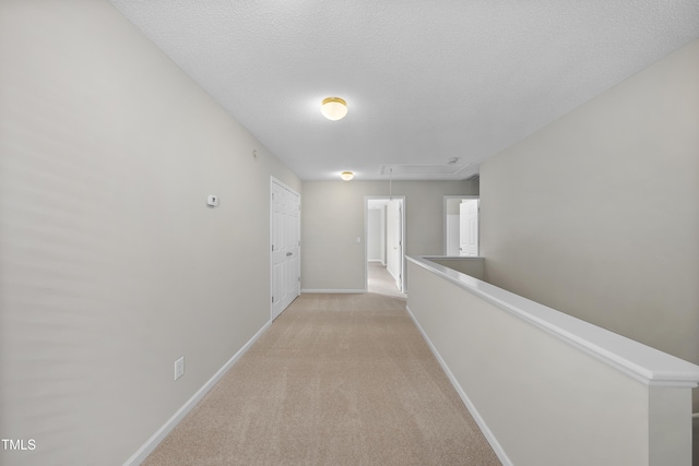 hall featuring light colored carpet and a textured ceiling