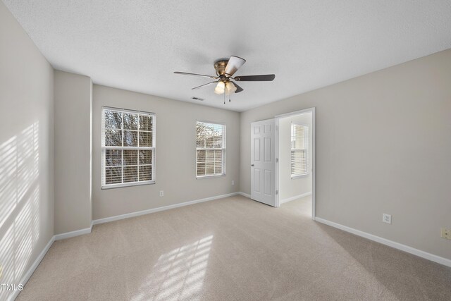 spare room featuring light carpet, ceiling fan, and a textured ceiling