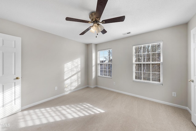 empty room featuring ceiling fan, light colored carpet, and a textured ceiling