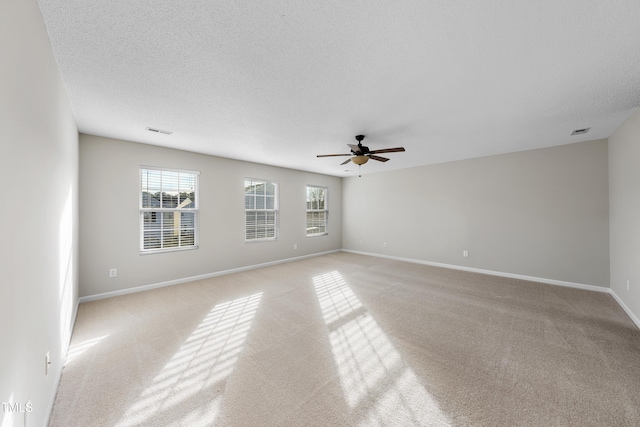 unfurnished room with a textured ceiling, ceiling fan, and light carpet