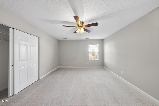 unfurnished bedroom with a closet, a textured ceiling, light colored carpet, and ceiling fan