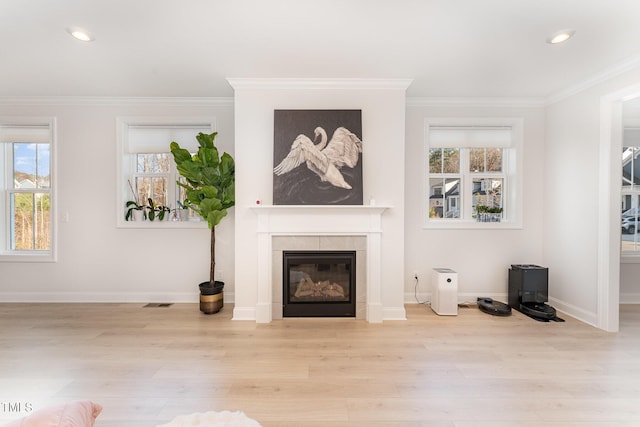 living room with light hardwood / wood-style flooring, ornamental molding, and a tiled fireplace