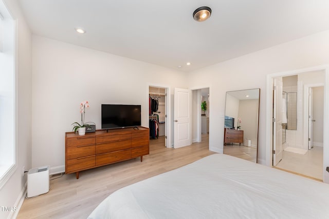 bedroom with a walk in closet, light wood-type flooring, connected bathroom, and a closet