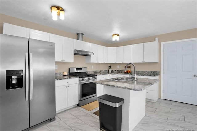 kitchen with stainless steel appliances, sink, stone counters, white cabinetry, and an island with sink