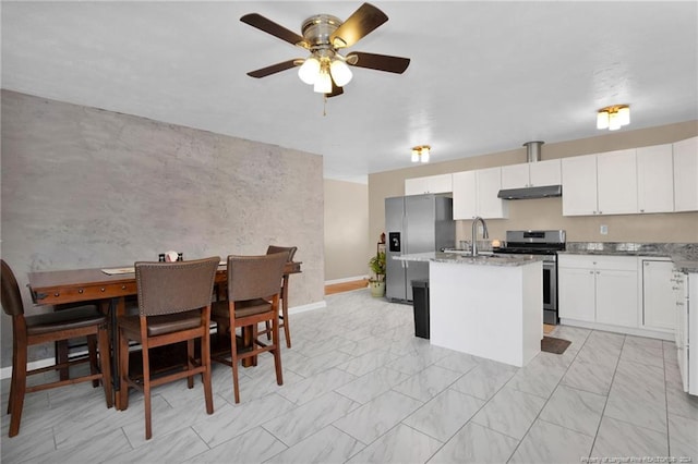 kitchen with white cabinets, appliances with stainless steel finishes, a kitchen island with sink, and ceiling fan