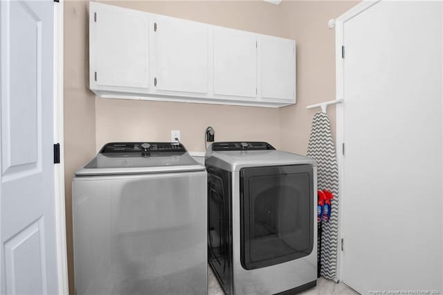 washroom featuring washer and clothes dryer and cabinets