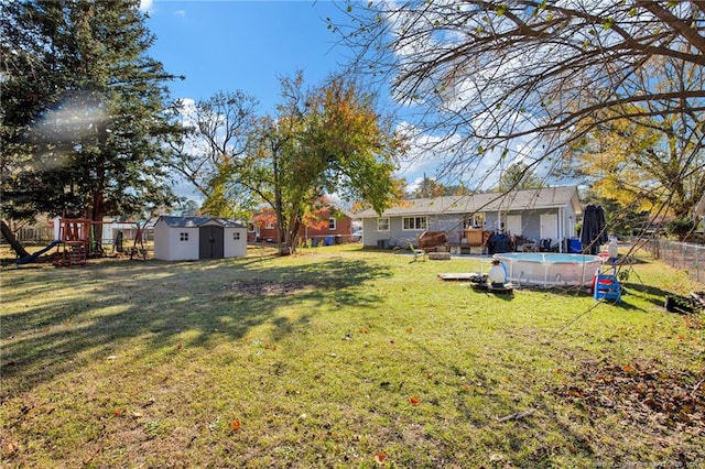 view of yard with a fenced in pool, a playground, and a storage unit