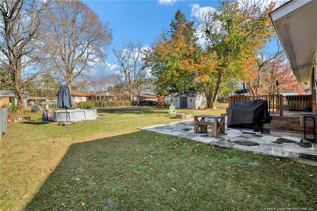 view of yard featuring a swimming pool side deck, a patio area, and a storage shed