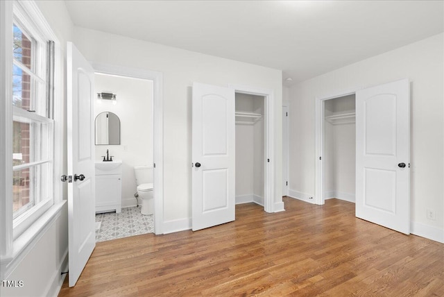 303 Forest Rd, Oxford, NC 27565 - unfurnished bedroom featuring light wood finished floors, multiple closets, and ensuite bath