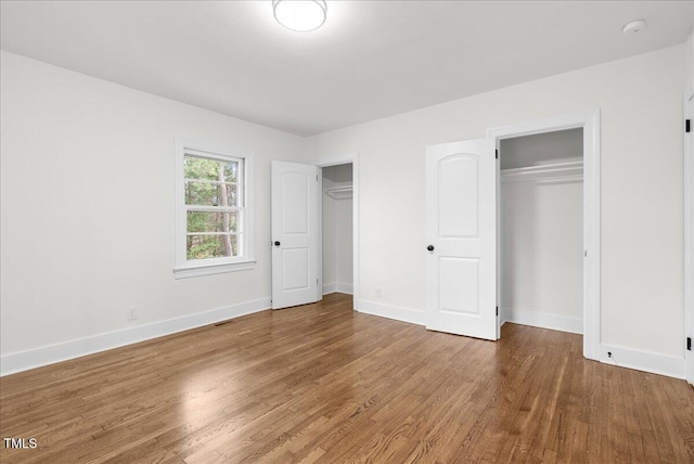 303 Forest Rd, Oxford, NC 27565 - unfurnished bedroom featuring multiple closets and wood finished floors