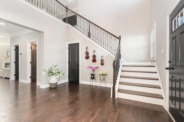 foyer entrance featuring a high ceiling, dark wood-type flooring, and ornamental molding