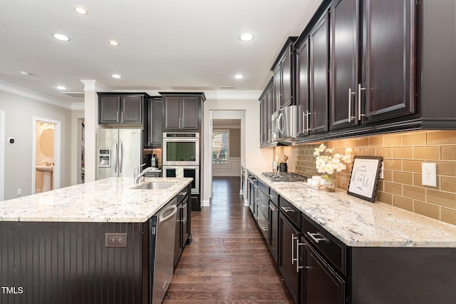 kitchen featuring appliances with stainless steel finishes, crown molding, sink, dark hardwood / wood-style floors, and an island with sink