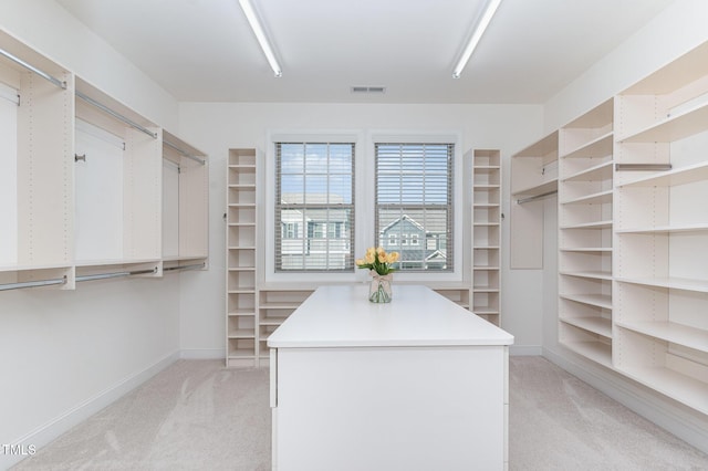 walk in closet with light carpet