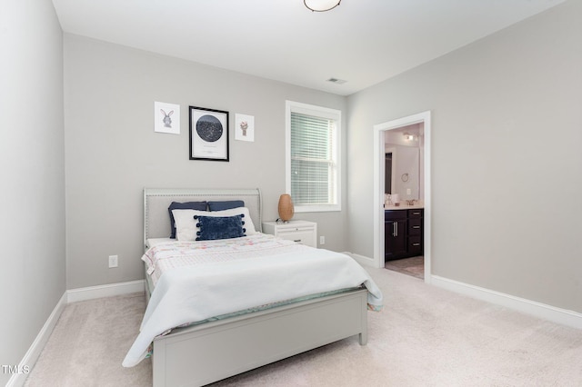 bedroom featuring light colored carpet and ensuite bath