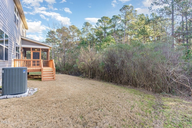 view of yard featuring a sunroom, central air condition unit, and a wooden deck