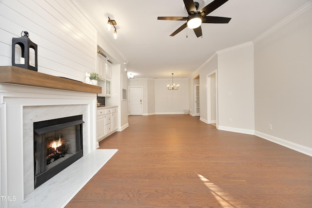 unfurnished living room with a fireplace, crown molding, light hardwood / wood-style flooring, and ceiling fan with notable chandelier