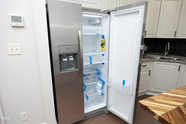 kitchen with white cabinets, stainless steel refrigerator with ice dispenser, decorative backsplash, and sink