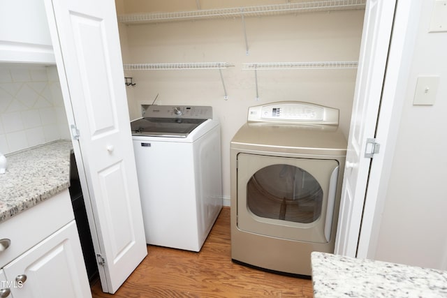 laundry area featuring separate washer and dryer and light hardwood / wood-style flooring