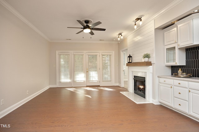 unfurnished living room with crown molding, a fireplace, ceiling fan, and dark hardwood / wood-style floors