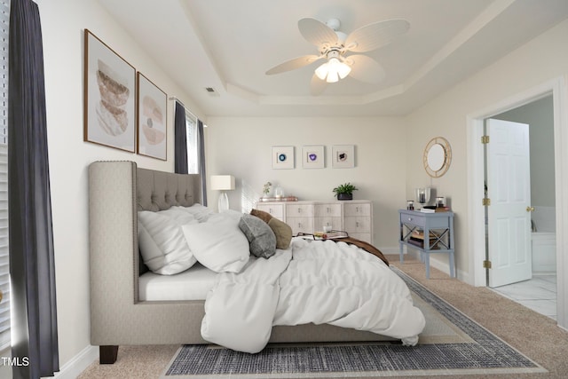 bedroom with ceiling fan, light colored carpet, and a tray ceiling