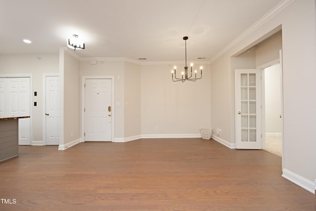 unfurnished room featuring hardwood / wood-style floors, an inviting chandelier, and crown molding