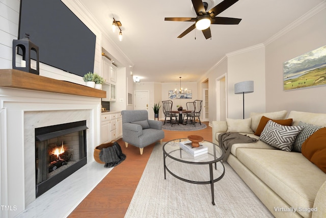 living room featuring a premium fireplace, ceiling fan, ornamental molding, and light hardwood / wood-style flooring