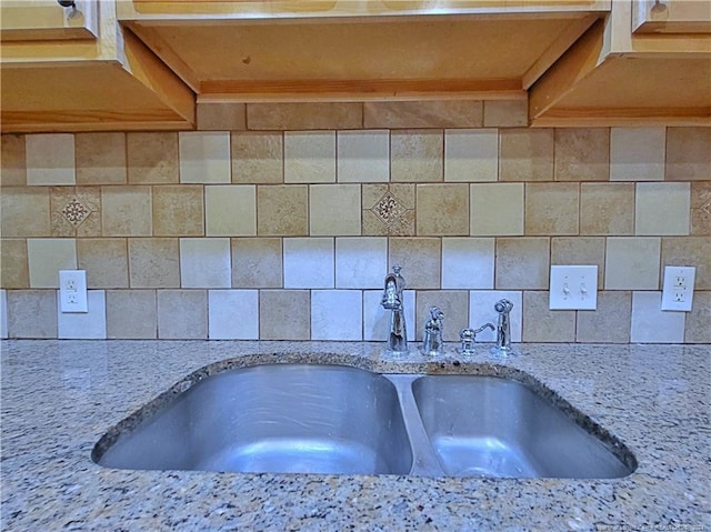 kitchen with decorative backsplash, sink, and light stone counters