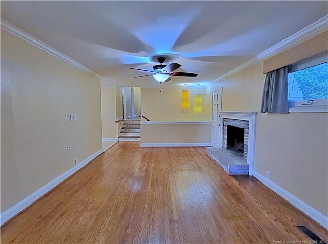 unfurnished living room featuring ceiling fan, light hardwood / wood-style floors, ornamental molding, and a brick fireplace