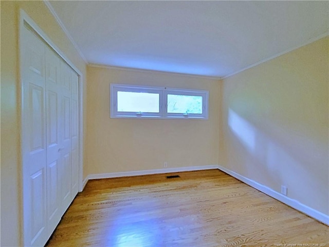 unfurnished bedroom featuring light hardwood / wood-style flooring, a closet, and ornamental molding