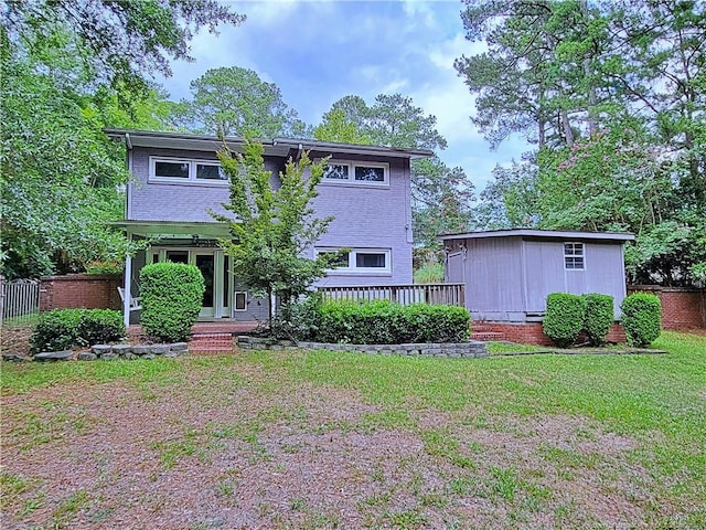 rear view of house featuring french doors, a wooden deck, and a lawn