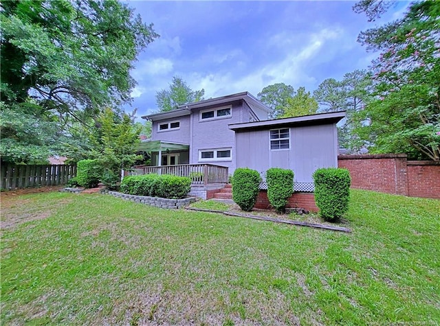 back of property with a deck and a lawn