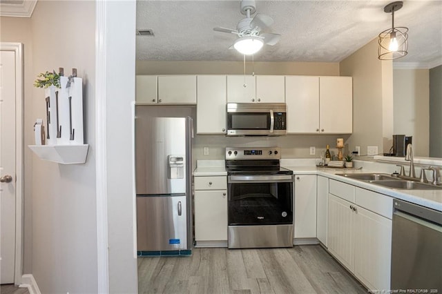 kitchen featuring sink, pendant lighting, a textured ceiling, white cabinets, and appliances with stainless steel finishes