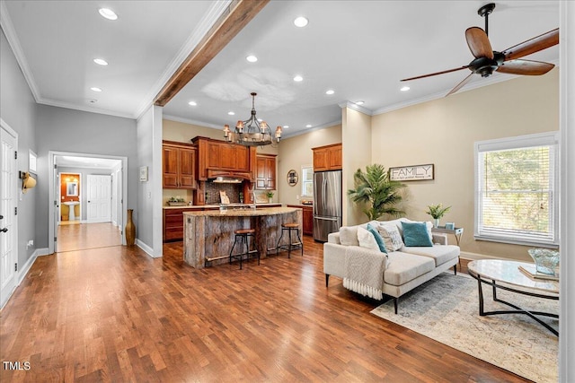 living room with sink, dark hardwood / wood-style floors, crown molding, and ceiling fan with notable chandelier