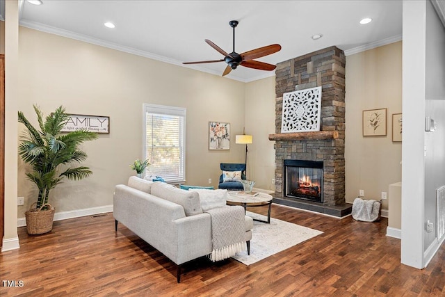 living room with a stone fireplace, ceiling fan, crown molding, and dark hardwood / wood-style floors