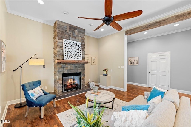 living room with ceiling fan, a stone fireplace, ornamental molding, and dark hardwood / wood-style floors