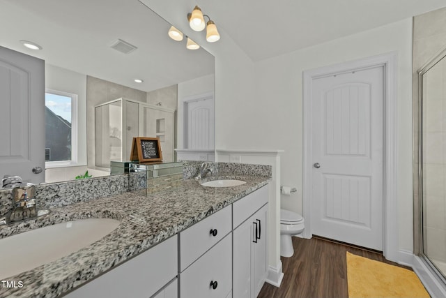 bathroom featuring hardwood / wood-style floors, vanity, toilet, and a shower with shower door