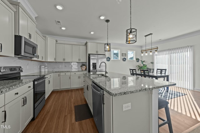 kitchen featuring pendant lighting, a kitchen island with sink, dark wood-type flooring, a kitchen breakfast bar, and stainless steel appliances