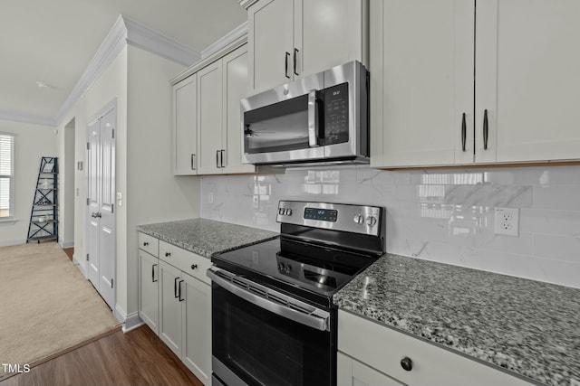 kitchen with light stone countertops, ornamental molding, dark hardwood / wood-style floors, and appliances with stainless steel finishes