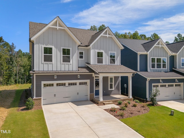 view of front of house featuring covered porch, a front yard, and a garage