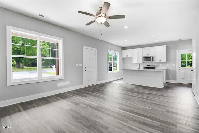 unfurnished living room featuring ceiling fan and dark hardwood / wood-style floors