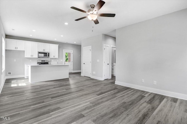 unfurnished living room with dark hardwood / wood-style flooring and ceiling fan