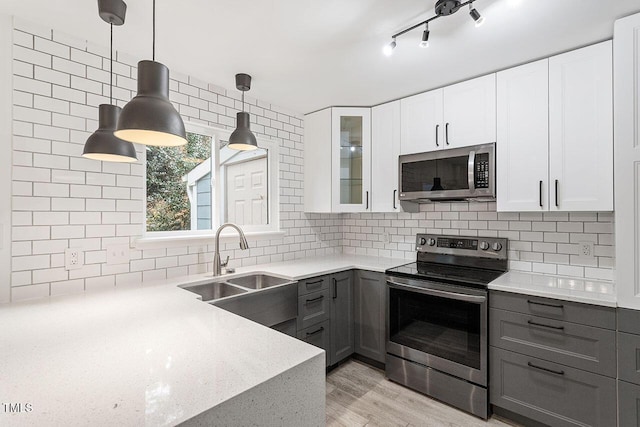 kitchen with gray cabinetry, stainless steel appliances, sink, pendant lighting, and white cabinets