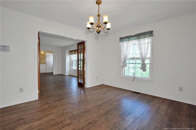 empty room featuring dark hardwood / wood-style flooring and a chandelier