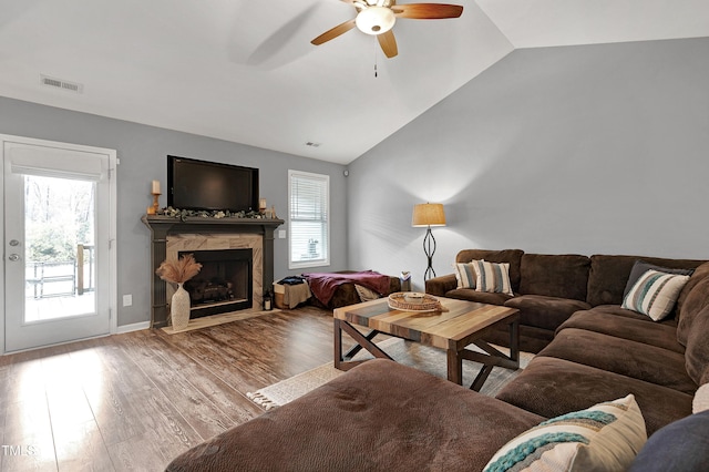 living room featuring ceiling fan, a high end fireplace, vaulted ceiling, and hardwood / wood-style flooring