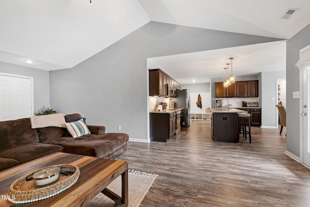 living room with dark hardwood / wood-style floors, lofted ceiling, and sink